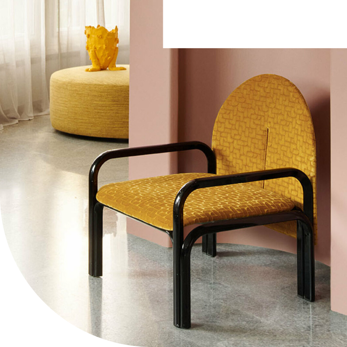 A modern chair with a mustard yellow cushion and black frame, placed against a pink wall in a stylish interior.